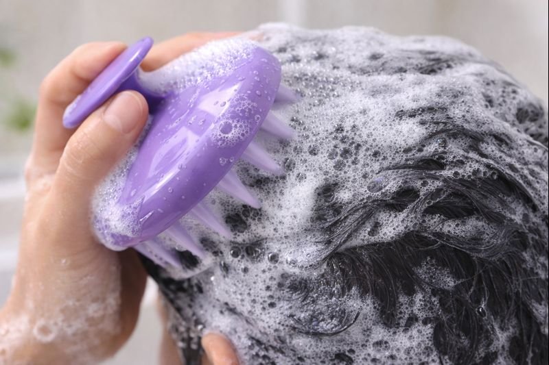 Person using scalp massager with shampoo
